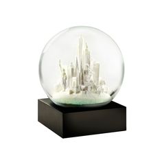 a snow globe with buildings in it on a black stand and white background is shown