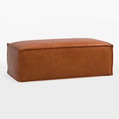 a brown leather ottoman sitting on top of a white floor