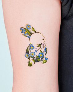 a tattoo on the arm of a woman with flowers and a bunny in it's ears