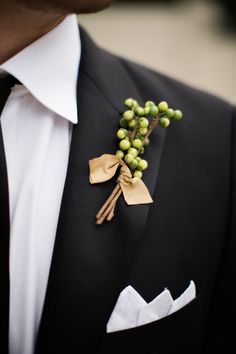 a man wearing a black suit and white shirt with a boutonniere on his lapel