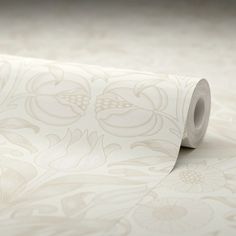 a roll of white wallpaper with floral designs on the bottom and sides, laying on top of a floor