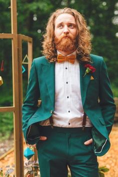 a man with long hair wearing a green suit and bow tie