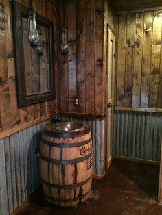 a wooden barrel sitting in the corner of a room next to a sink and mirror