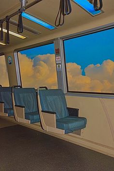 an empty train car with blue seats looking out the windows at clouds in the sky