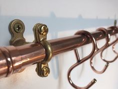 two metal hooks are attached to the side of a curtain rod with brass hardware on it