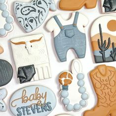 decorated cookies are arranged in the shape of cowboy boots and baby clothes, with words on them