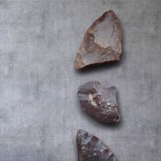 three pieces of rock sitting on top of a cement floor next to each other,