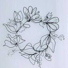 a wire wreath with leaves and vines hanging from it's sides on a white wall