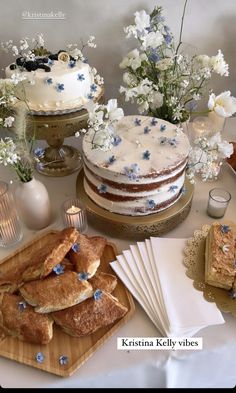 a table topped with cakes and desserts on top of wooden cutting boards next to flowers