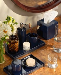 two blue trays with soap, toothbrushes and other bathroom accessories on a wooden table