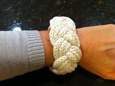 a person's arm with a bracelet made out of white knitted yarn on it