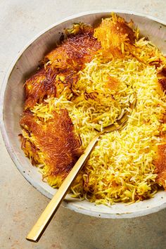 a bowl filled with yellow food next to a wooden spoon