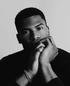 a black and white photo of a man with his hand on his chin looking at the camera