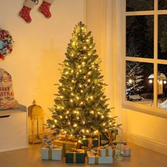 a christmas tree with presents under it in front of a window