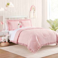 a bedroom with pink bedding and white walls in the background is an unicorn themed room