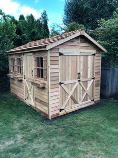 a small wooden shed sitting on top of a lush green field