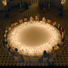 an overhead view of people sitting in chairs around a table with candles on the floor