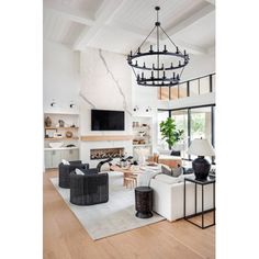 a living room filled with furniture and a chandelier hanging over the fire place