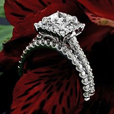 a diamond ring sitting on top of a red flower