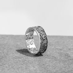 a silver ring sitting on top of a gray surface next to a white wall and floor