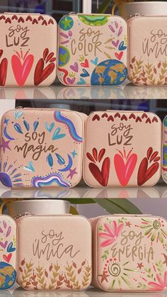 four different colored tins with the words love written on them and hearts painted on them