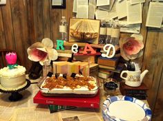 a table topped with cakes and books covered in frosting next to a cake on top of a plate