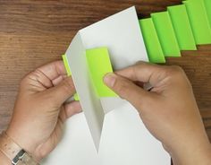 someone is cutting out some green paper on top of a piece of white paper with scissors