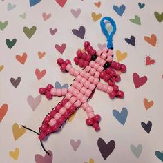 a cross made out of beads on top of a sheet of paper with hearts in the background