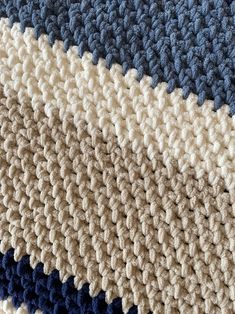 a close up view of a crocheted blanket with blue, beige and white colors