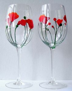 two wine glasses with red flowers painted on the bottom and green stems in the middle