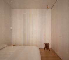 a white bed sitting in a bedroom next to a wooden stool