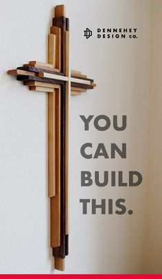 a wooden cross hanging on the wall next to a sign that says you can build this