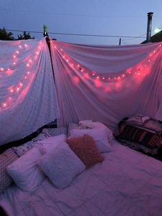 a bed covered in pink lights and pillows