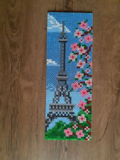 a cross - stitch picture of the eiffel tower with pink flowers on it