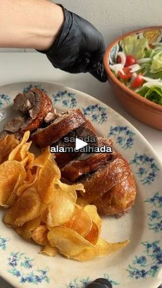 a plate with chips and meat on it next to a bowl full of lettuce