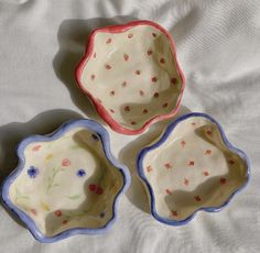 three small dishes sitting on top of a bed