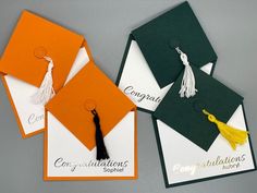 three graduation caps with tassels and congratulations written on the front, two are orange, one is green