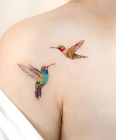 two hummingbirds on the back of a woman's shoulder