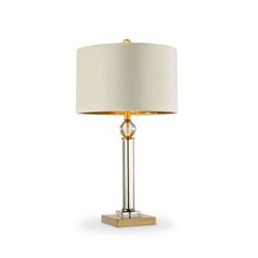 a table lamp with a white shade on the base and a gold metal frame around it