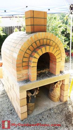 an outdoor brick pizza oven in the middle of gravel