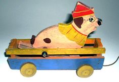 a wooden toy dog riding in a wagon