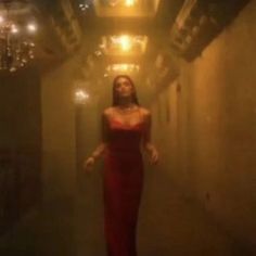 a woman in a red dress walking down a hallway