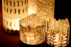 three lit candles sitting next to each other on top of a wooden table covered in paper