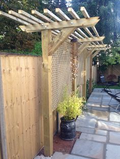 a wooden pergolated area with a potted plant next to it