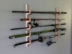 a wall mounted fishing rod rack with several different types of rods and reels on it