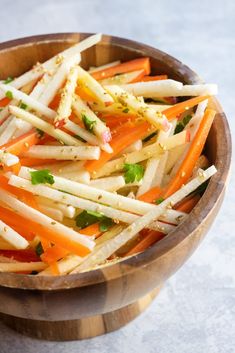 a wooden bowl filled with carrots, parsley and other veggie toppings