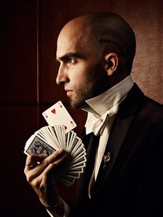 a man in a tuxedo holding playing cards