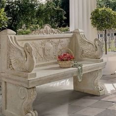 a white marble bench sitting on top of a tiled floor next to a tree filled with flowers