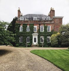 a large brick building with ivy growing on it's sides and two driveways leading to the front door