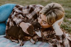 a woman laying on top of a blanket holding a dog